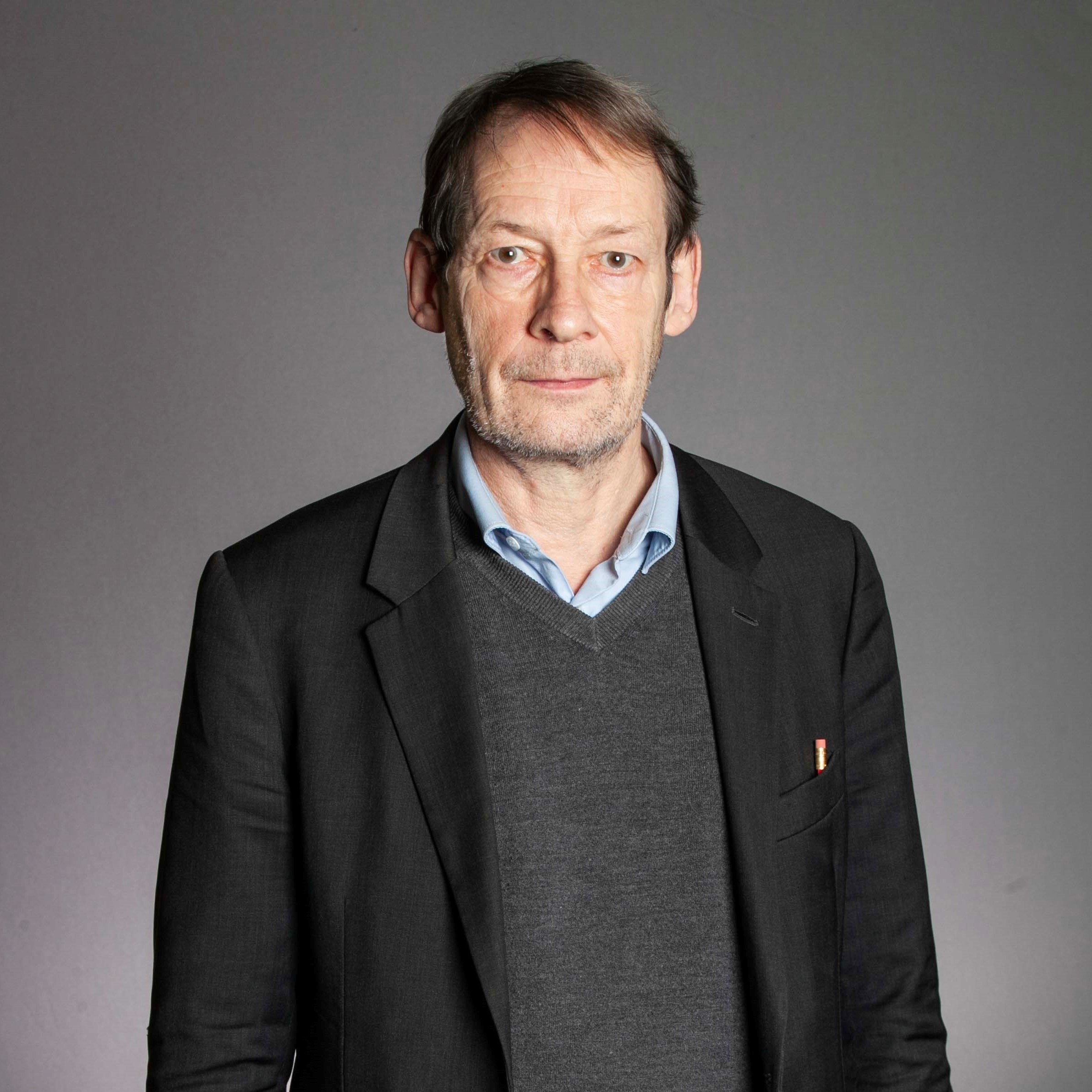Nick Gay headshot in dark jacket and jumper